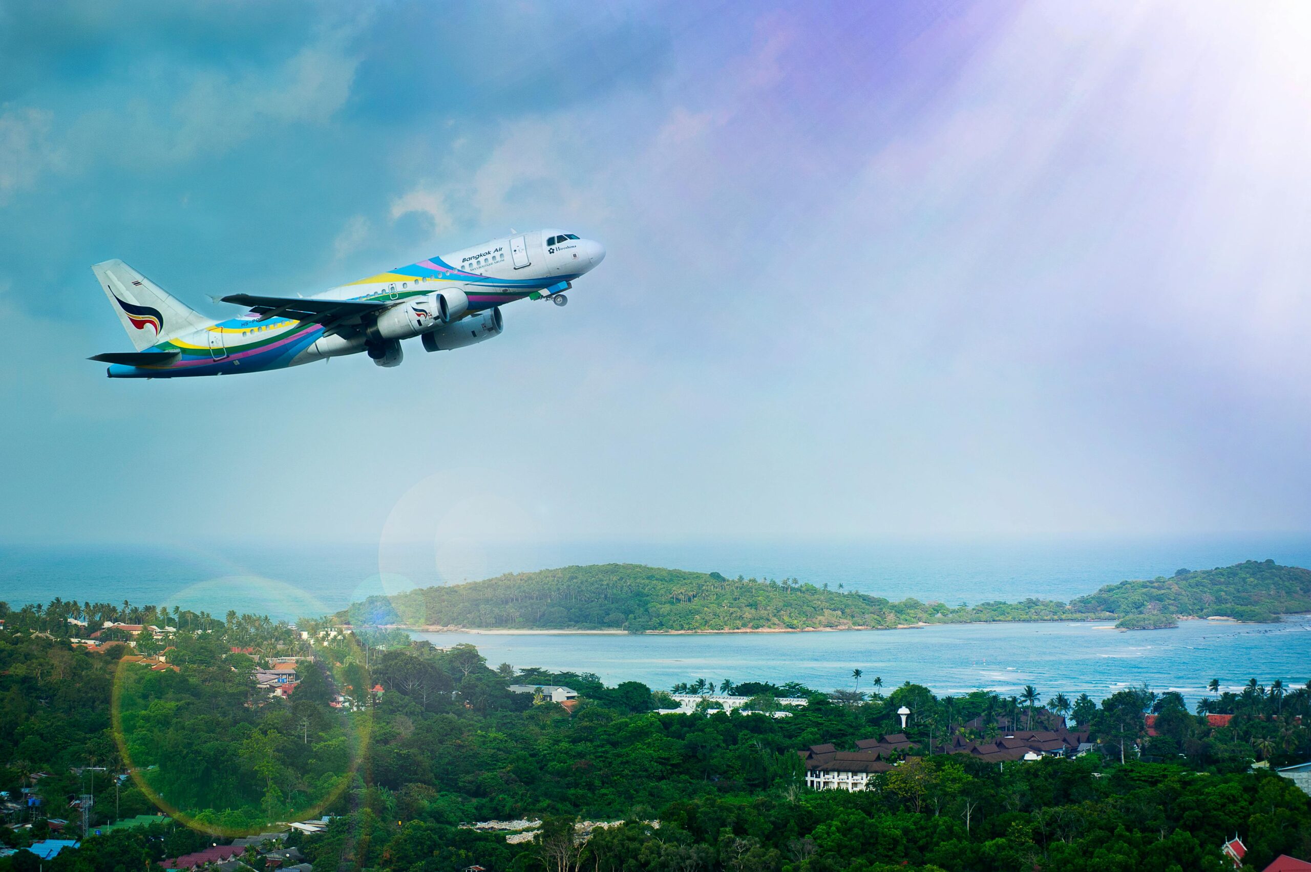 Airplane flying into a blue and purple sky over an island.