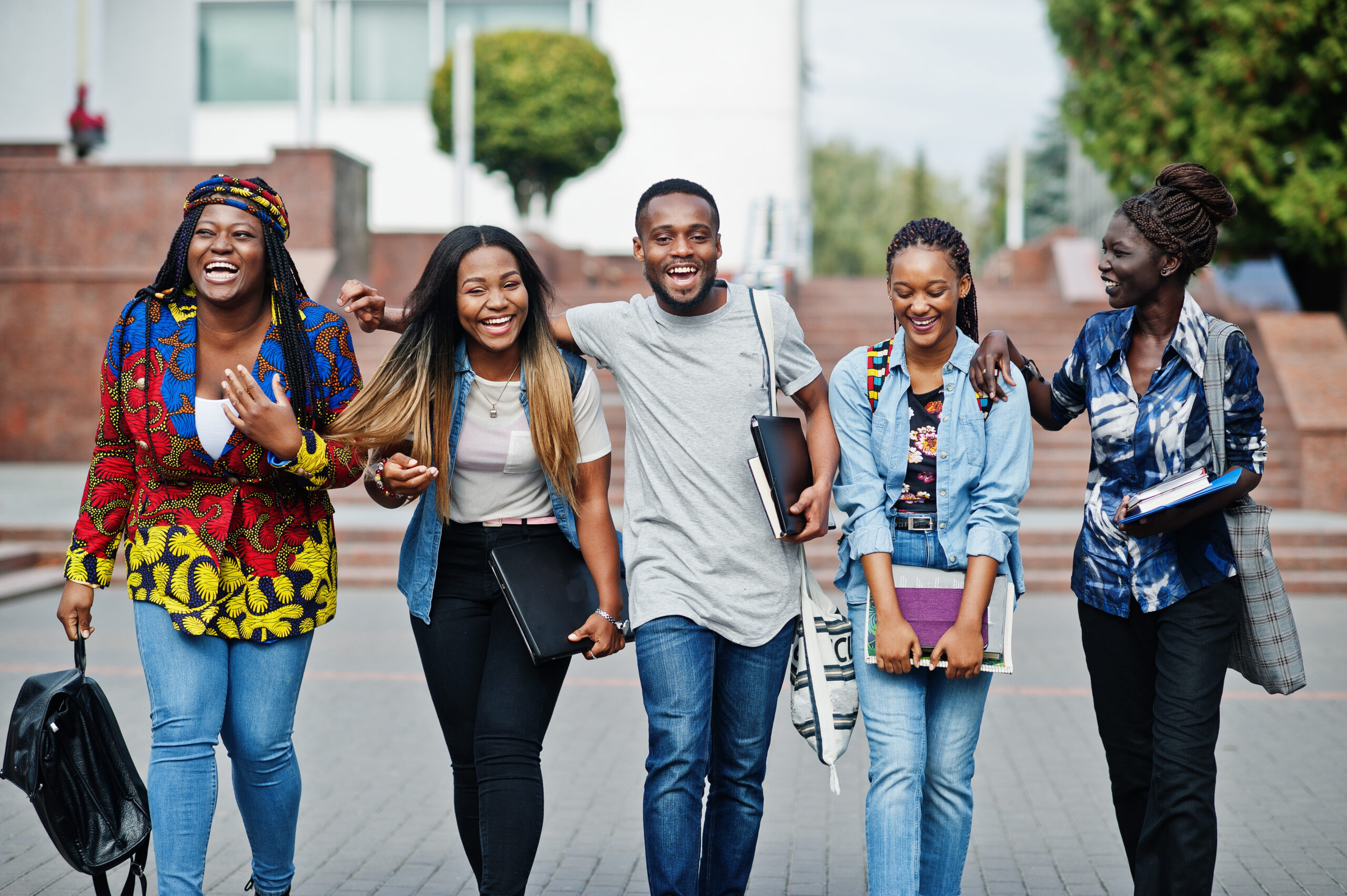 5 students walking next to each other on a college campus.